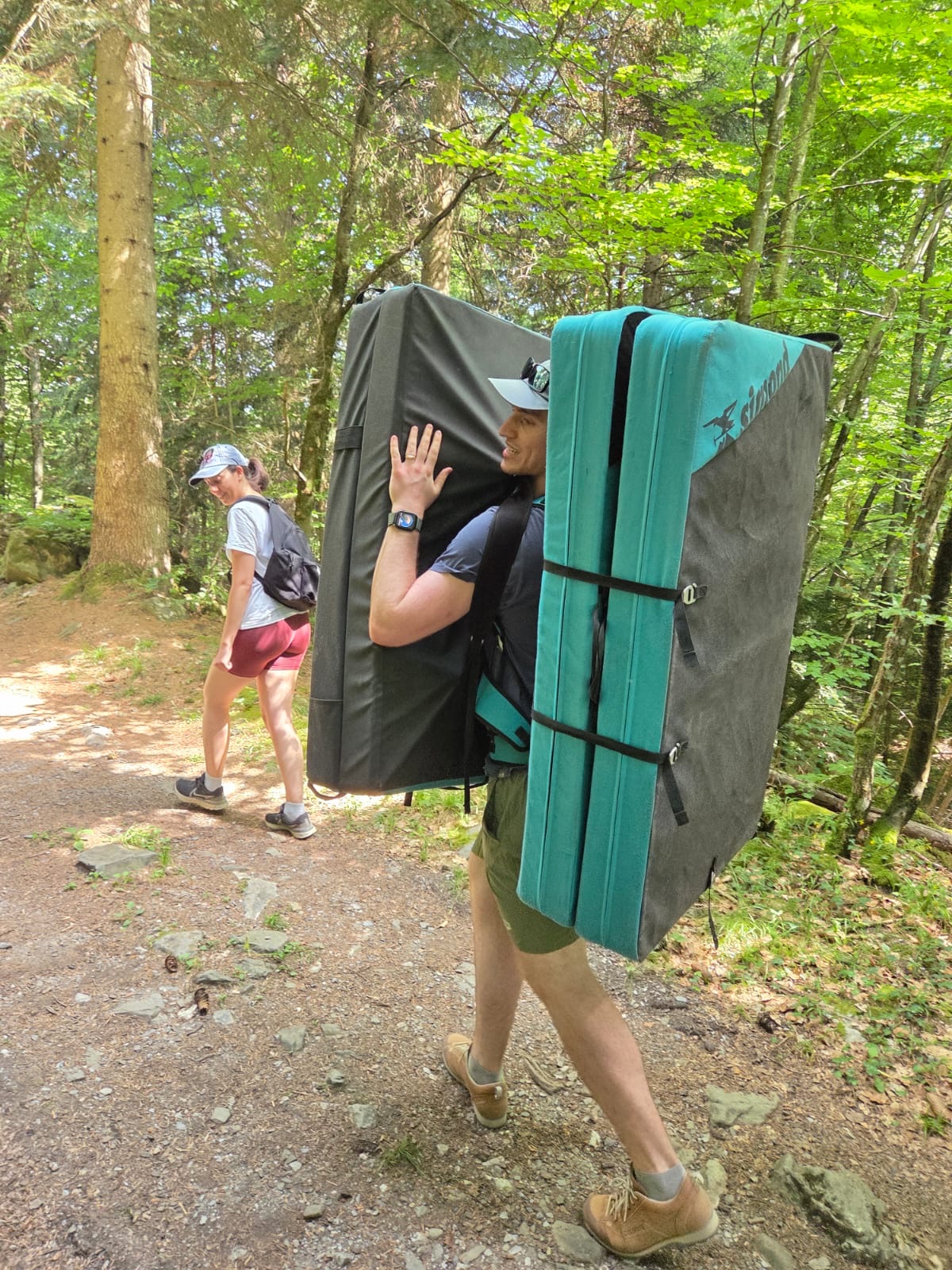 Jacob carrying crash pads while approaching an outdoor bouldering area