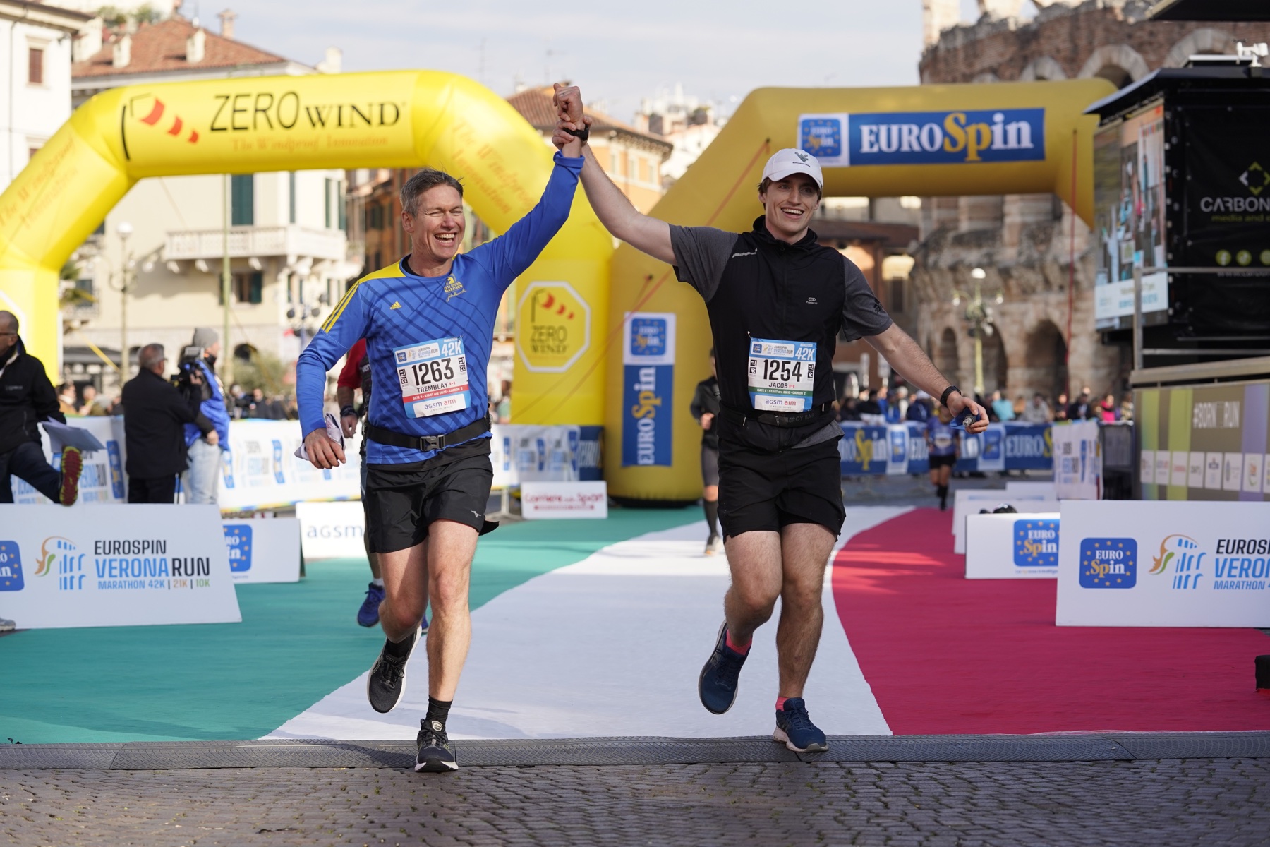 Jacob crossing the Verona Marathon finish line with another runner