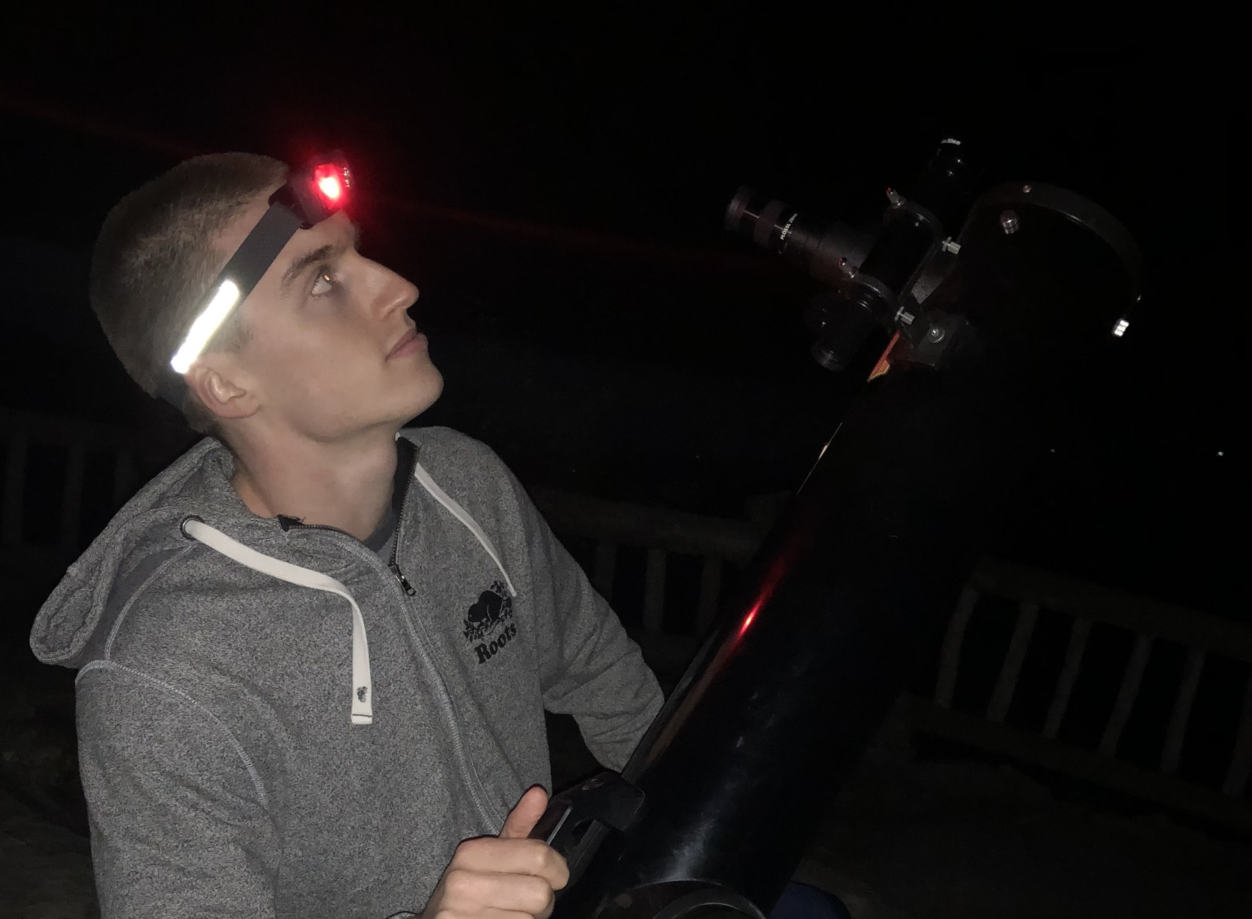 An observer using a telescope beneath the night sky